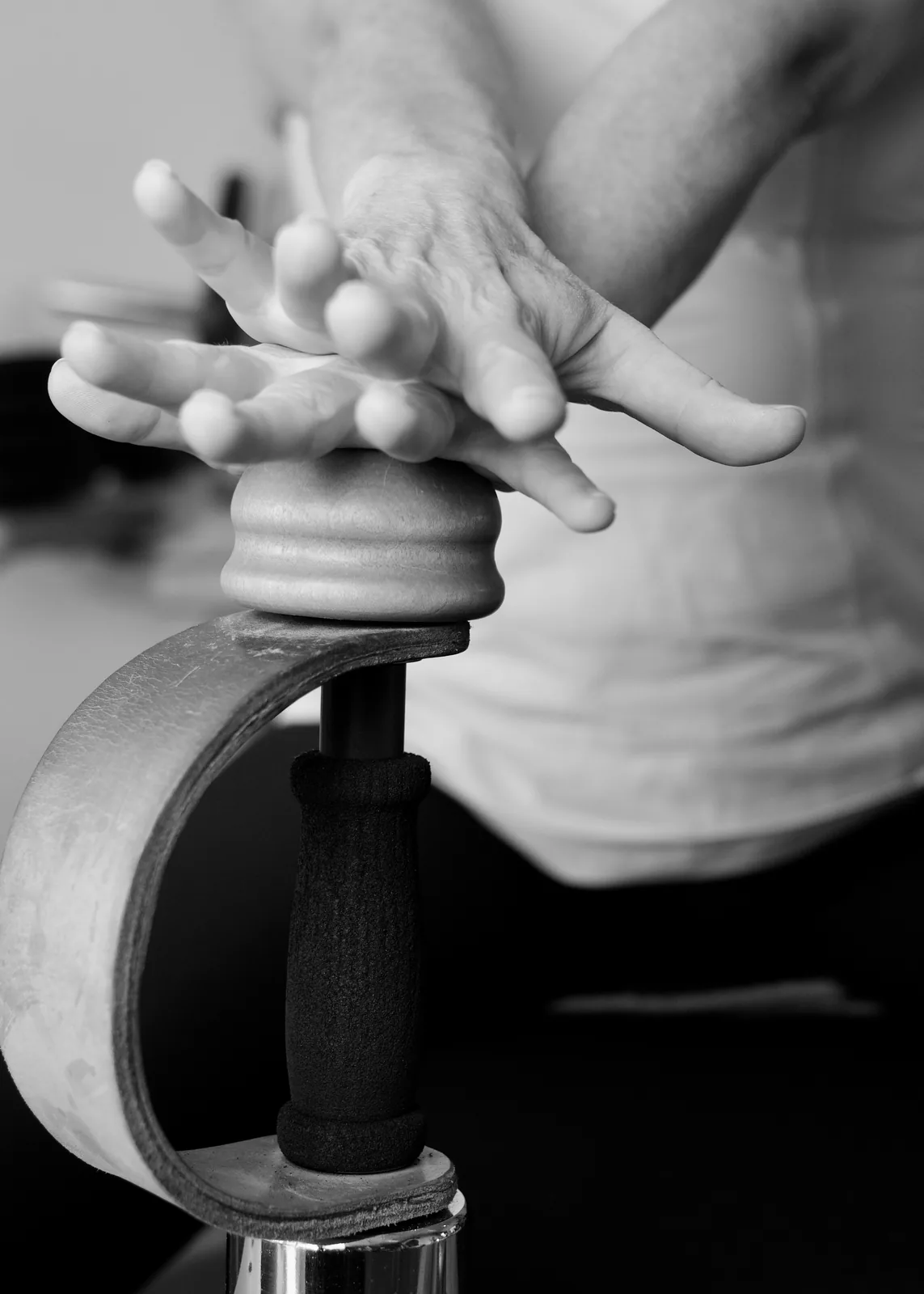Hands resting on a Gyrotonic tower handle — a quiet moment of contact with the equipment
